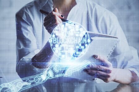 Cryptocurrency hologram, bitcoin, ico theme over hands taking notes background. Concept of...