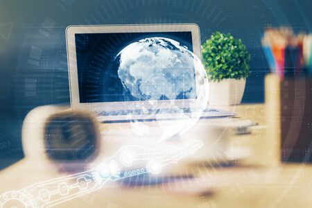 Double exposure of desktop with computer and world map hologram. International data network concept.