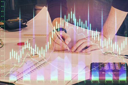 Double exposure of man writing on paper with forex graph. Concept of research and trading.