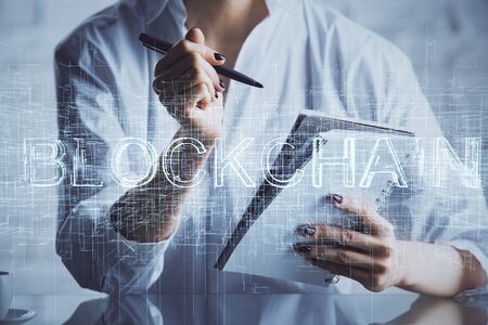 Cryptocurrency hologram, bitcoin, ico theme over hands taking notes background. Concept of blockchain. Multi exposureの写真素材
