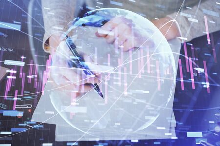 Hands macking notes in notepad. Forex chart holograms in front. Concept of research. Multi exposureの写真素材