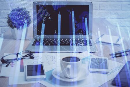 Stock market graph on background with desk and personal computer. Multi exposure. Concept of financial analysis.の写真素材