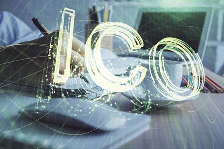 Cryptocurrency hologram, bitcoin, ico theme over hands taking notes background. Concept of...