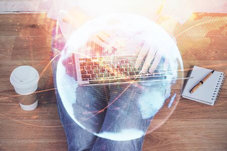 Double exposure of businessman working on laptop on background. International business hologram in front. Concept of success.の写真素材