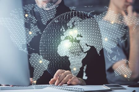 Double exposure of businessman working on laptop on background. International business hologram in...