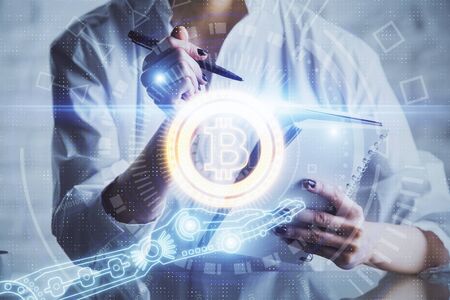 Cryptocurrency hologram, bitcoin, ico theme over hands taking notes background. Concept of...