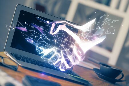 Desktop computer background in office and handshake hologram drawing. Double exposure. Pertnership concept.の写真素材