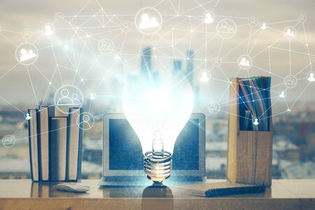 Computer on desktop in office with bulb icon hologram. Multi exposure. Concept of idea.の写真素材