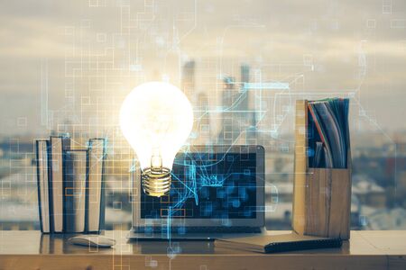 Computer on desktop in office with bulb icon hologram. Multi exposure. Concept of idea.の写真素材