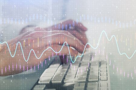 Double exposure of graph with man typing on computer in office on background. Concept of hard work....