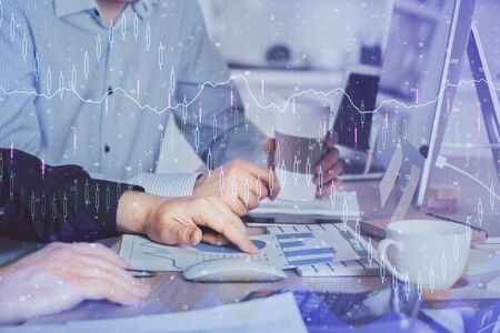 Multi exposure of chart with man typing on computer in office on background. Concept of hard work.の写真素材