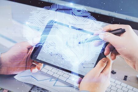 Double exposure of mans hand holding and using a digital device and brain hologram drawing. Data...