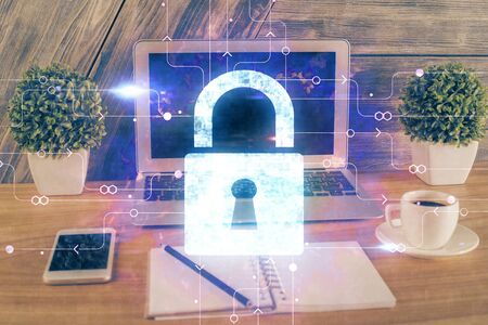 Double exposure of desktop with computer and lock icon hologram. Concept of data safety.