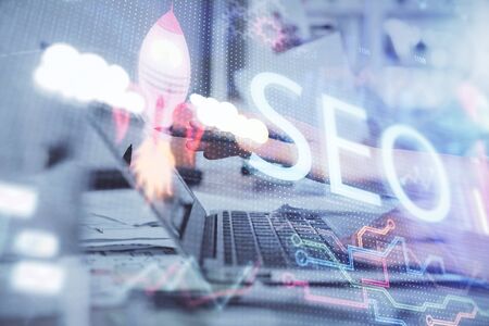 Double exposure of woman hands working on computer and seo hologram drawing. internet search concept.の写真素材