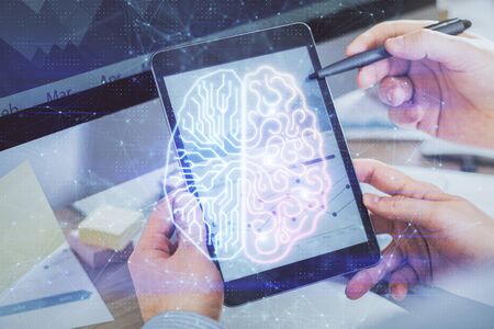 Double exposure of man's hand holding and using a digital device and brain hologram drawing. Data concept.の写真素材
