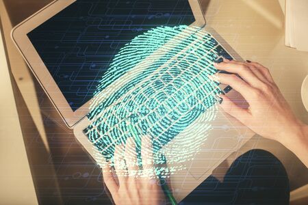 Double exposure of woman hands working on computer and fingerprint hologram drawing. Top View....