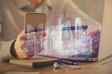 Double exposure of man hands holding a credit card and city drawing. modern town and E-commerce pay...
