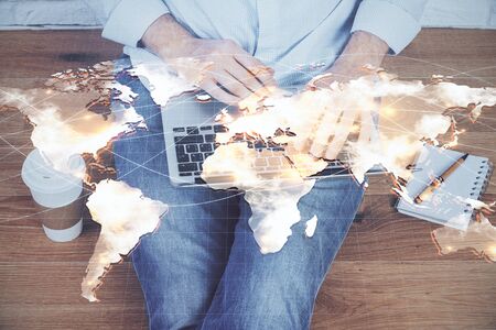 Double exposure of businessman working on laptop on background. International business hologram in front. Concept of success.の写真素材