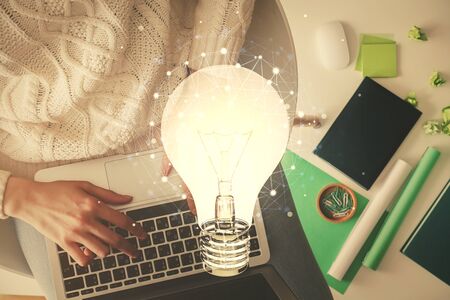 Double exposure of woman hands working on computer and light bulb hologram drawing. Top View. Idea concept.の写真素材
