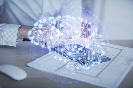 Double exposure of man's hand holding and using a digital device and brain hologram drawing. Data...