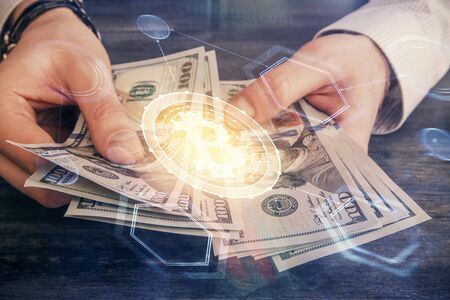 Multi exposure of blockchain theme drawing hologram and USA dollars bills and man hands. Business...
