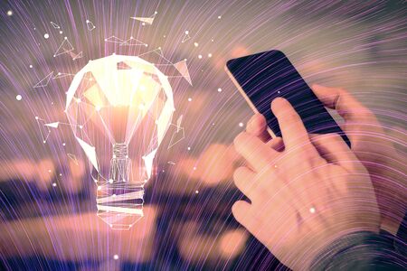 Double exposure of man's hands holding and using a digital device and bulb hologram drawing. Idea concept.の写真素材