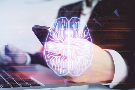 Double exposure of man's hand holding and using a digital device and brain hologram drawing. Data...