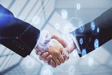 Double exposure of data theme hologram and handshake of two men. Partnership in IT industry concept.