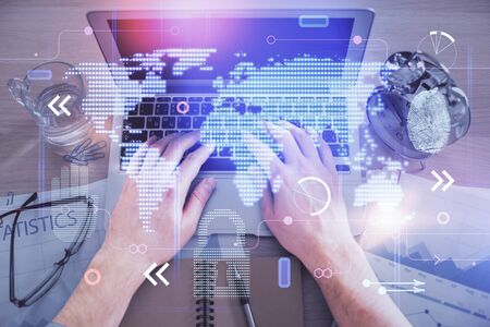 Multi exposure of mans hands typing over computer keyboard and world map hologram drawing. Top view. Technology concept.の写真素材
