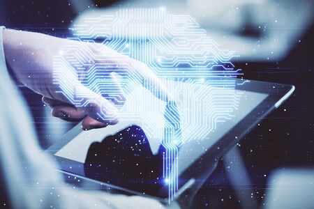 Double exposure of man's hand holding and using a digital device and brain hologram drawing. Data...