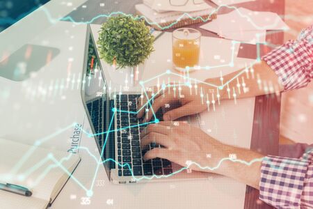 Multi exposure of graph with man typing on computer in office on background. Concept of hard work. Closeup.の写真素材