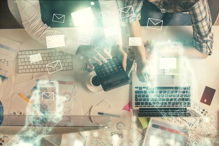 Double exposure of man and woman working together and the envelop hologram drawing. Computer background. Top View. Electronic mail concept.の写真素材