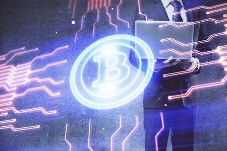 Crypto currency theme hologram with businessman working on computer on background. Concept of blockchain. Double exposure.の写真素材