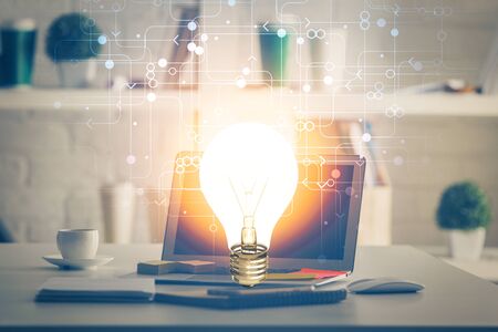Computer on desktop in office with bulb icon hologram. Multi exposure. Concept of idea.の写真素材