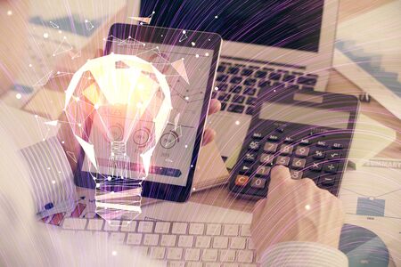 Double exposure of mans hands holding and using a digital device and bulb hologram drawing. Idea concept.の写真素材