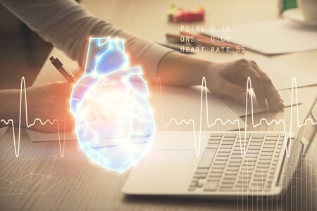 Double exposure of woman hands typing on computer and heart hologram drawing. Education concept.の写真素材