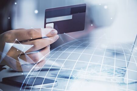 Double exposure of woman on-line shopping holding a credit card and world map hologram drawing. International E-commerce concept.の写真素材