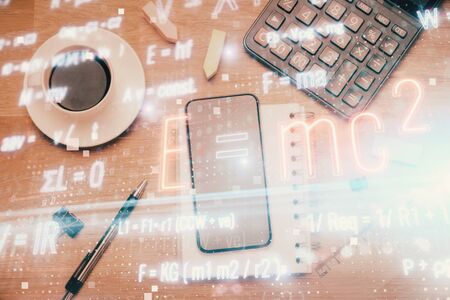 Double exposure of formula drawing over table with phone. Top view. Education concept.の写真素材