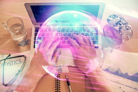 Double exposure of mans hands typing over computer keyboard and tech theme hologram drawing. Top view. Technology concept.の写真素材