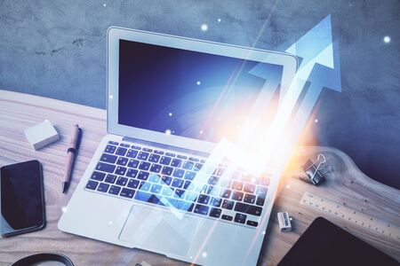 Computer on desktop with point up arrows hologram. Double exposure. Concept of success.の写真素材