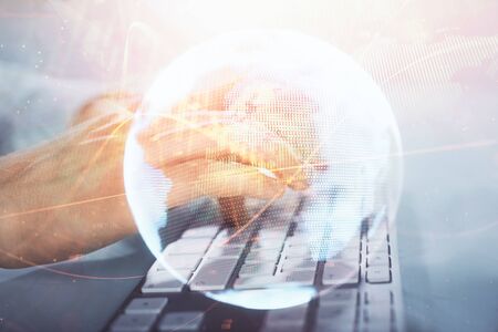 Double exposure of businessman working on laptop on background. International business hologram in front. Concept of success.の写真素材