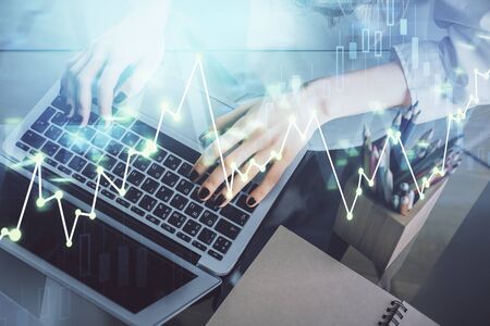 Double exposure of woman hands typing on computer and forex chart hologram drawing. Stock market...