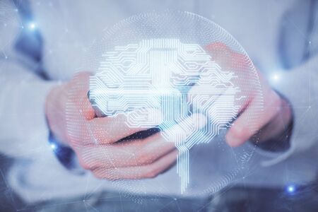 Double exposure of man's hand holding and using a digital device and brain hologram drawing. Data...