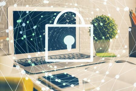 Double exposure of desktop with computer and lock icon hologram. Concept of data safety.