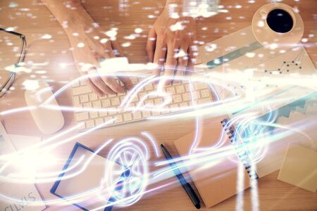 Double exposure of man's hands typing over computer keyboard and automobile theme hologram drawing. Top view. Technology concept.の写真素材