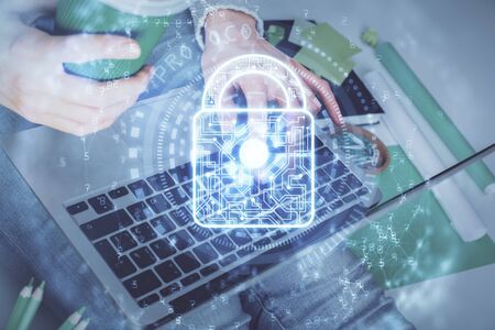 Double exposure of woman hands working on computer and lock hologram drawing. Security concept.