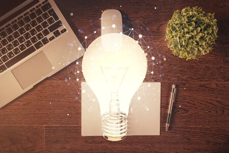 Bulb drawing over computer on the desktop background. Top view. Double exposure. Idea concept.の写真素材