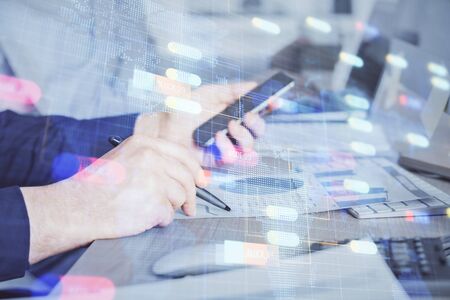 Double exposure of mans hand holding and using a digital device and data theme hologram drawing. Technology concept.の写真素材