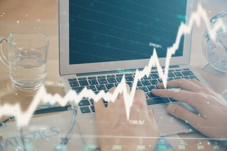 Multi exposure of market chart with man working on computer on background. Concept of financial...