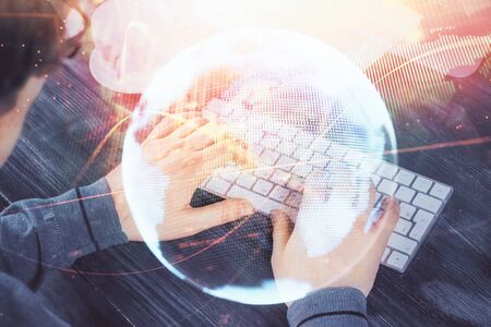 Double exposure of businessman working on laptop on background. International business hologram in front. Concept of success.の写真素材